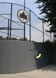 This high concrete wall surrounds the southeast corner of the ballfield.