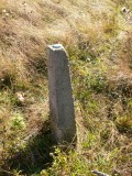 An eyelevel view of the post in the meadow. The concrete is slightly eroded but in decent condition.