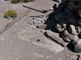 Eyelevel view of the station disk set in rock outcrop at cairn base.